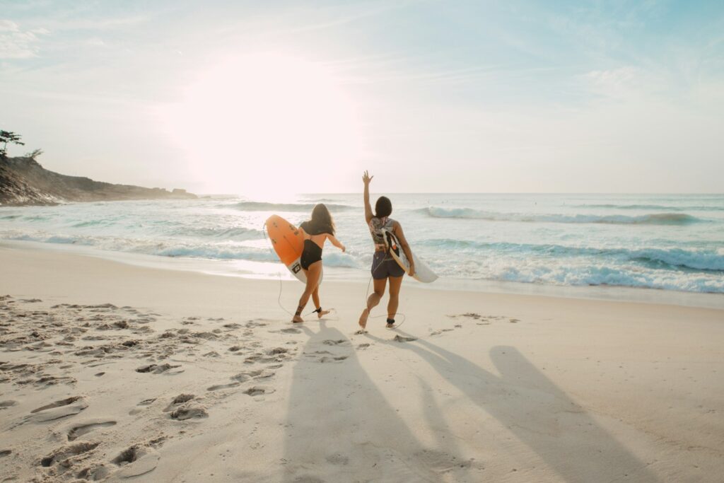 Dwie surferki z deskami idące w stronę oceanu o zachodzie słońca na plaży Playa Venao w Panamie