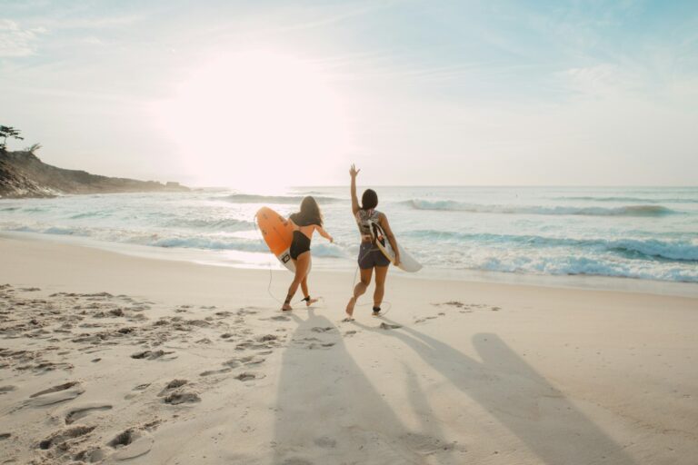 Dwie surferki z deskami idące w stronę oceanu o zachodzie słońca na plaży Playa Venao w Panamie