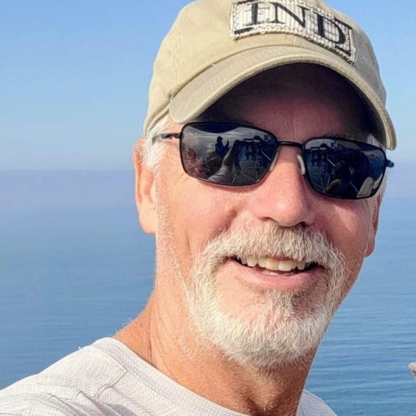 Dave, kapitan katamaranu Ohana, w czapce i okularach przeciwsłonecznych na tle morza